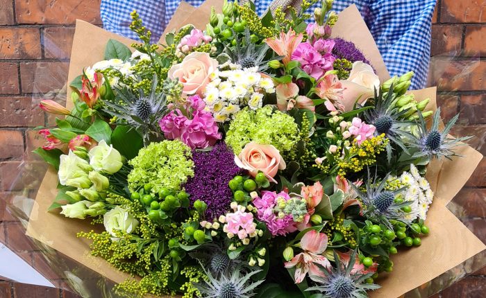 image of a close up of staff members personally designed mothers day bouquet, presented in a wild style in rustic colours.