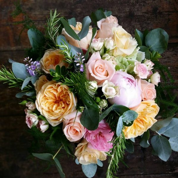 Image of a wild style bridal bouquet featuring peach vintage roses, pink roses and mixed foliage