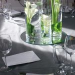 image showing a selection of different height vases with cala lillies on a wedding dining table