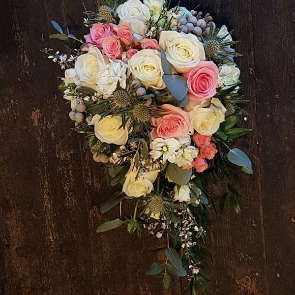 image of a teardrop shaped bridal bouquet featuring pink, peach and white roses