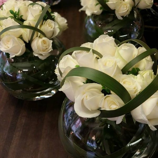 image showing modern style white rose arrangements with artistic greenery in medium fish bowl vases