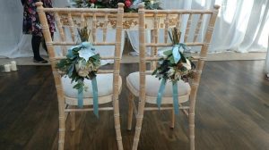 Image showing 2 chairs with white rustic style pew end bouquets tied to the back