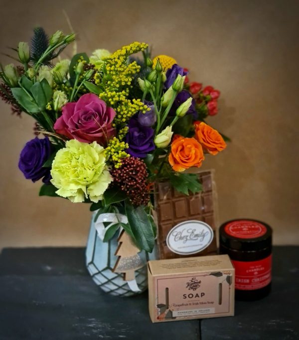 Image of the stocking filler gift set, featuring a compact bouquet in a jar, a bar of milk chocolate by Chez Emily, a bar of soap by the Handmade soap company, and a festive candle by the Irish chandler