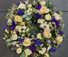 Image of a large funeral wreath by Adonis presented in rich purples and whites