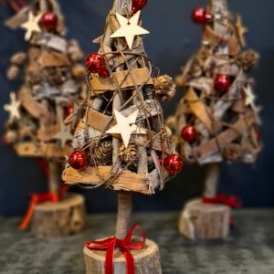 Image of 3 small christmas trees made of wood and bark, decorated with birch stars, tiny pine cones and red baubles.